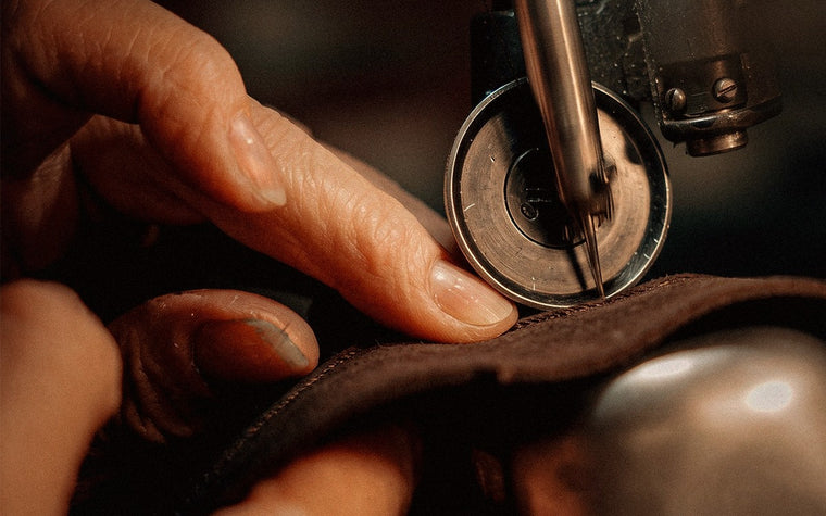 Mãos costurando um chapéu no ateliê — ofício e herança